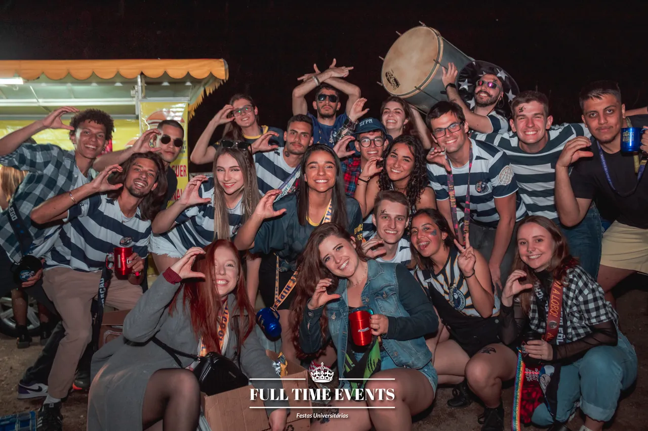 Galera da atlética com camisas listradas posando reunida em festa noturna