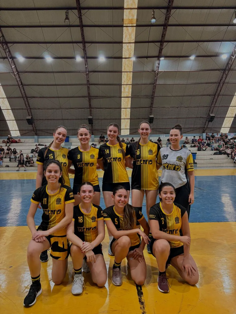 Time feminino da atlética uniformizado posando no ginásio