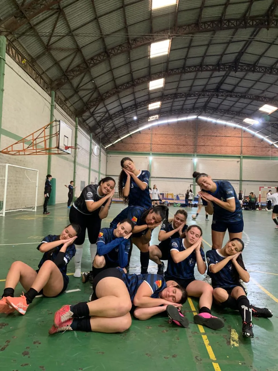 Time feminino da atlética fazendo pose divertida na quadra